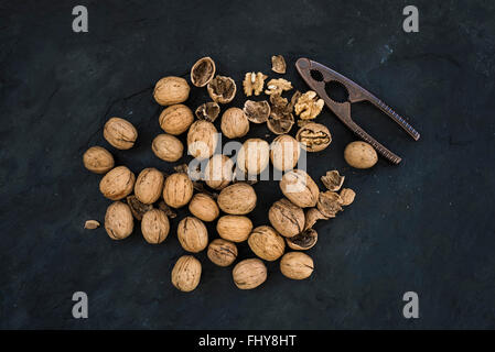 Walnuts with nutcracker over  black slate stone background top view Stock Photo