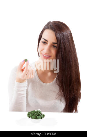 Detox. Beautiful girl with green pills on spoon isolated on white. Spirulina, chlorella and wheatgrass. Healthy lifestyle, detox Stock Photo