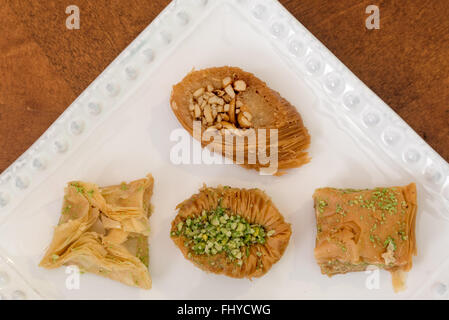 Delicious baklava covered with pistachio and almonds,  displayed on a white plate, traditional Greek pastry, enjoyed best as des Stock Photo