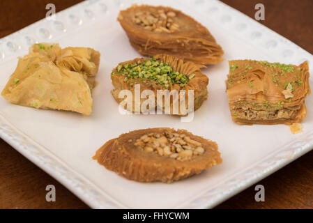 Delicious baklava covered with pistachio and almonds,  displayed on a white plate, traditional Greek pastry, enjoyed best as des Stock Photo