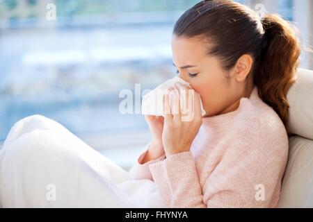 MODEL RELEASED. Woman blowing her nose. Stock Photo