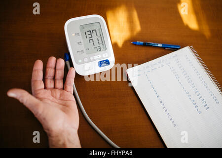 Hand of senior man controlling his blood pressure, close-up Stock Photo