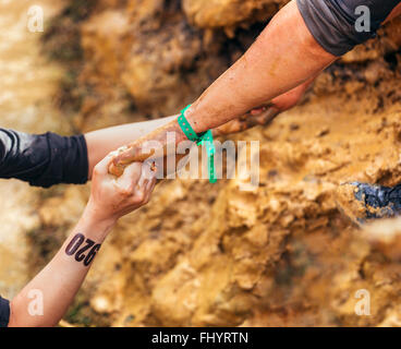 Participants in extreme obstacle race helping each other Stock Photo