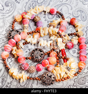 above view of tangled pink and yellow necklace from natural gemstones (pink Agate Dragon veins, horn, shell, mahogany obsidian b Stock Photo