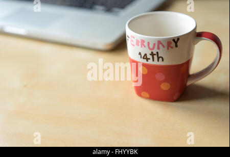 Empty valentine's cup with clipping path and a laptop, copy space on wooden table Stock Photo