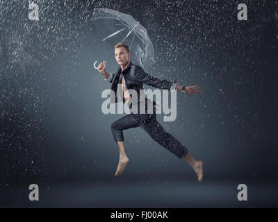 Handsome guy jumping and dancing in the rain Stock Photo