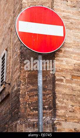 Round red sign No Entry on metal pole near old brick wall Stock Photo