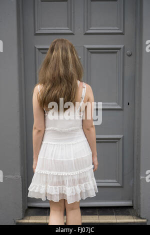 Woman in white dress standing by the door Stock Photo