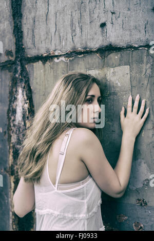 Scared young woman leaning against the wall Stock Photo