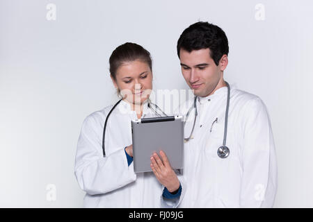 two young doctors, male and female in white coats, with stethoscope working with tablet pc Stock Photo