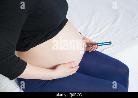 A nine month pregnant woman injects herself with rapid acting insulin Novorapid to control her Type 1 diabetes. Stock Photo