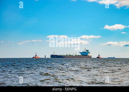 Tanker ship and tugboats moving in the sea. Stock Photo