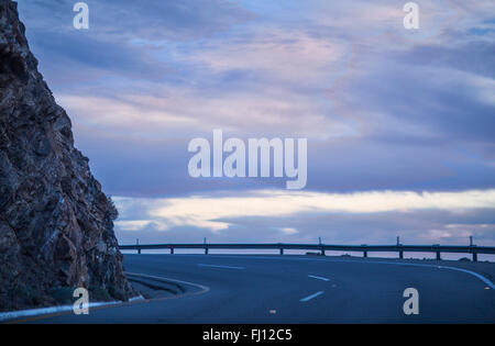 Road beside the cliff is dangerous. The tender blue sky gives dangerous hidden road a beautiful landscape. Stock Photo