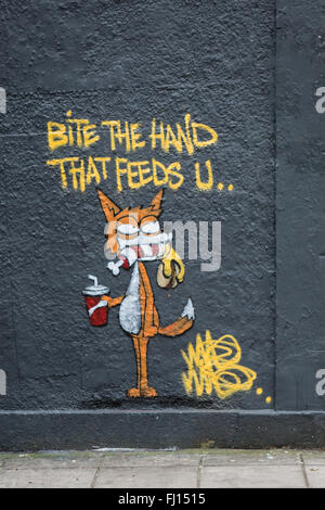 Bite the Hand that Feeds you Graffiti on the side of a building in Stokes Croft, Bristol Stock Photo