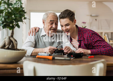 Portrait of senior man and grandson with toy train at home Stock Photo