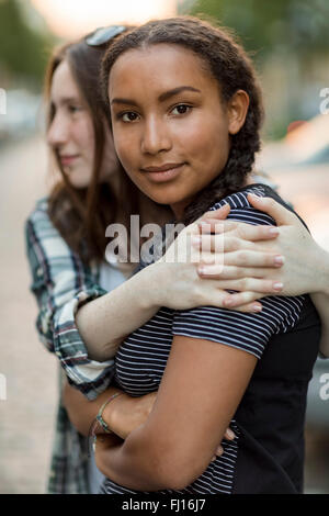 Two teenage girls hugging outdoors Stock Photo - Alamy