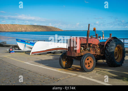 Coble Carr at Filey, North Yorkshire UK,  with small coble fishing boats and an old Fisherman's tractor in front of Filey Brigg Stock Photo