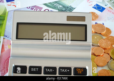 Close up of a blank screen of a pocket calculator in the background Euro banknotes and coins Stock Photo