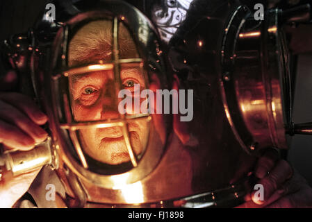 Person trying on a deep sea diving helmet at a dive exhibition in London. Stock Photo