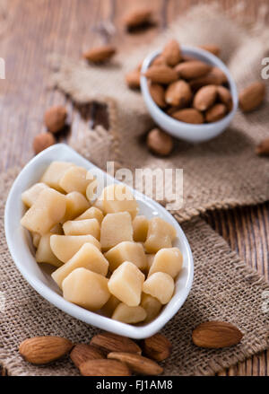 Raw Marzipan (close-up shot) with almonds on wooden background Stock Photo