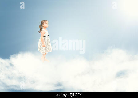 Cute little girl standing barefoot on  clouds Stock Photo