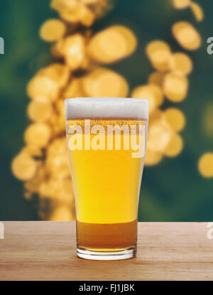 Glass of beer on wooden in light bokeh blurred background Stock Photo