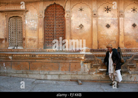 Man walks along haveli wall in street of  Jaisalmer , India Stock Photo