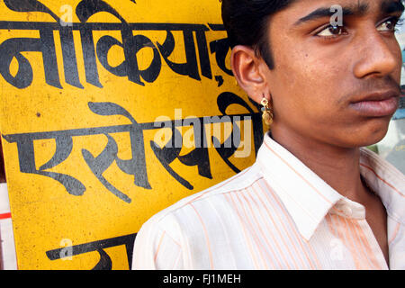 Indian Rajasthani man in Bikaner with earring and hindi writings in Bikaner , India Stock Photo