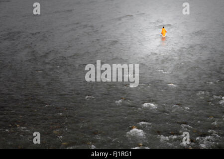 man with saffron dress walks alone in the water of the ganges during Kumbh mela, Haridwar Stock Photo