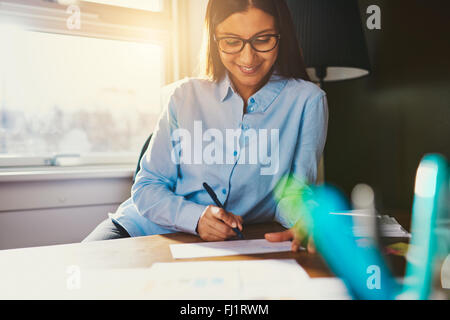 Business woman working at desk writing an address on a envelope Stock Photo