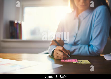 Closeup business woman writing notes on a post it Stock Photo