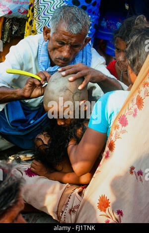 A kid gets shaved on the ghats in Varanasi, India Stock Photo