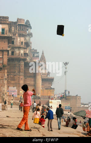 Kid playing kite on a ghat of Varanasi, India - Stock Photo