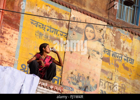Woman is drinking chaï tea in the early morning light in holy city Varanasi , India Stock Photo
