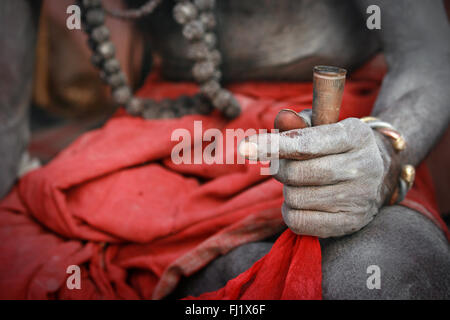 Sadhu - hand of holy man smoking chillum in clay pipe covered with ashes Stock Photo