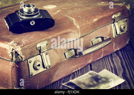 Old cracked stained suitcase with camera in vintage colors Stock Photo
