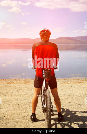 man with bike on a mountain lake Stock Photo