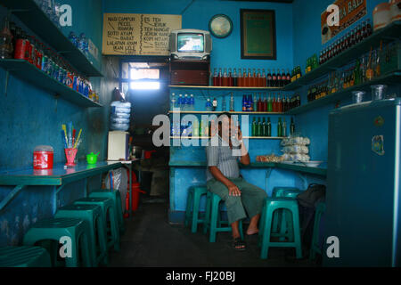 Man on the phone in tiny local restaurant in Denpasar , Bali Stock Photo