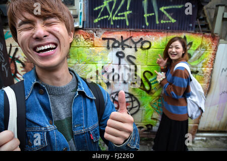 Two Japanese young people are having fun with writing "Tokyo is yours" on the wall - Welcome to Japan ! Stock Photo