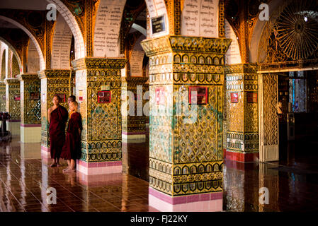 MANDALAY, Myanmar — The Sutaungpyei Pagoda sits atop Mandalay Hill, offering panoramic views of the city below. The gilded stupa of the pagoda gleams in the sunlight, surrounded by ornate pavilions and shrines. Visitors and pilgrims explore the temple complex, some pausing to pray or make offerings at the various Buddha statues. Stock Photo