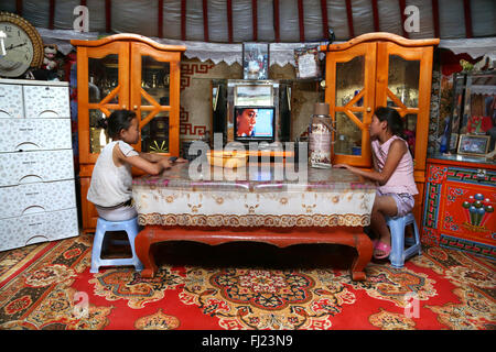 Two young girls are watching TV in a traditional home called ger or yurt in Mongolia Stock Photo