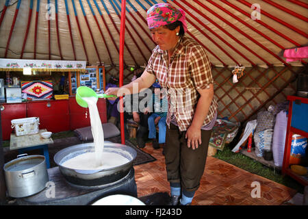 A nomad woman is boiling and preparing kumis traditional horse milk in a traditional yurt ger in Mongolia Stock Photo