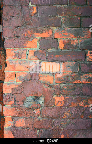 Obsolete brick wall painted in orange and dark violet Stock Photo