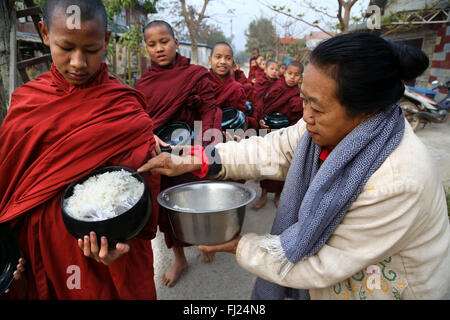 Buddhist monks receive rice from population, daily ritual, Nyaung-U, Myanmar Stock Photo