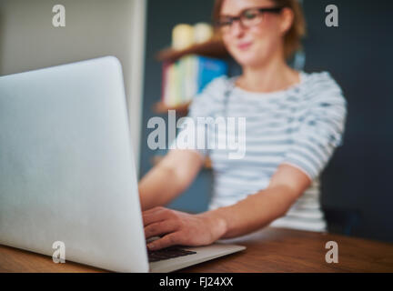 Closeup view of woman using laptop sitting in home office, blue colors Stock Photo