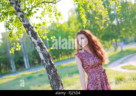 Beautiful red-haired girl in dress posing in nature Stock Photo