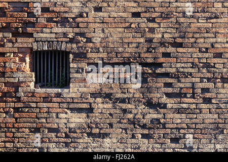 Ancient brick wall and window locked with metal bars Stock Photo