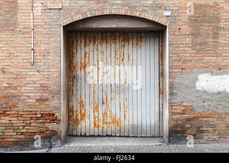 Rusted grungy metal gate in old brick wall, background photo texture Stock Photo
