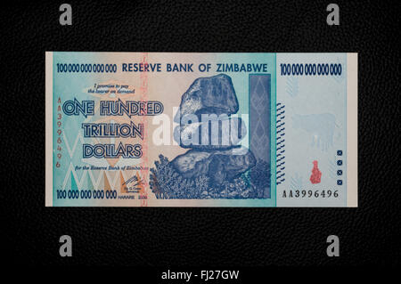 One hundred trillion dollars banknote issued in Zimbabwe in 2008, on the climax of the hyperinflation. Black background. Stock Photo