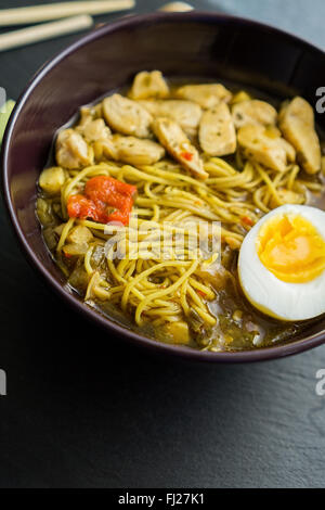 Chicken noodle ramen with egg and ingredients on a dark slate Stock Photo